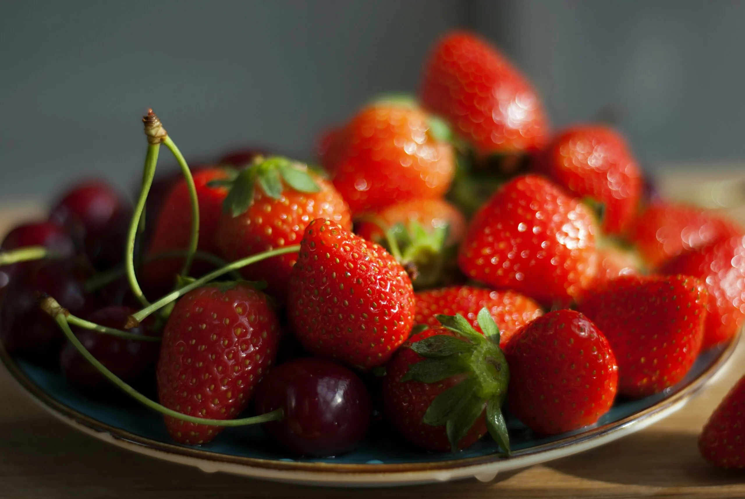 A plate of strawberries and cherries on a table