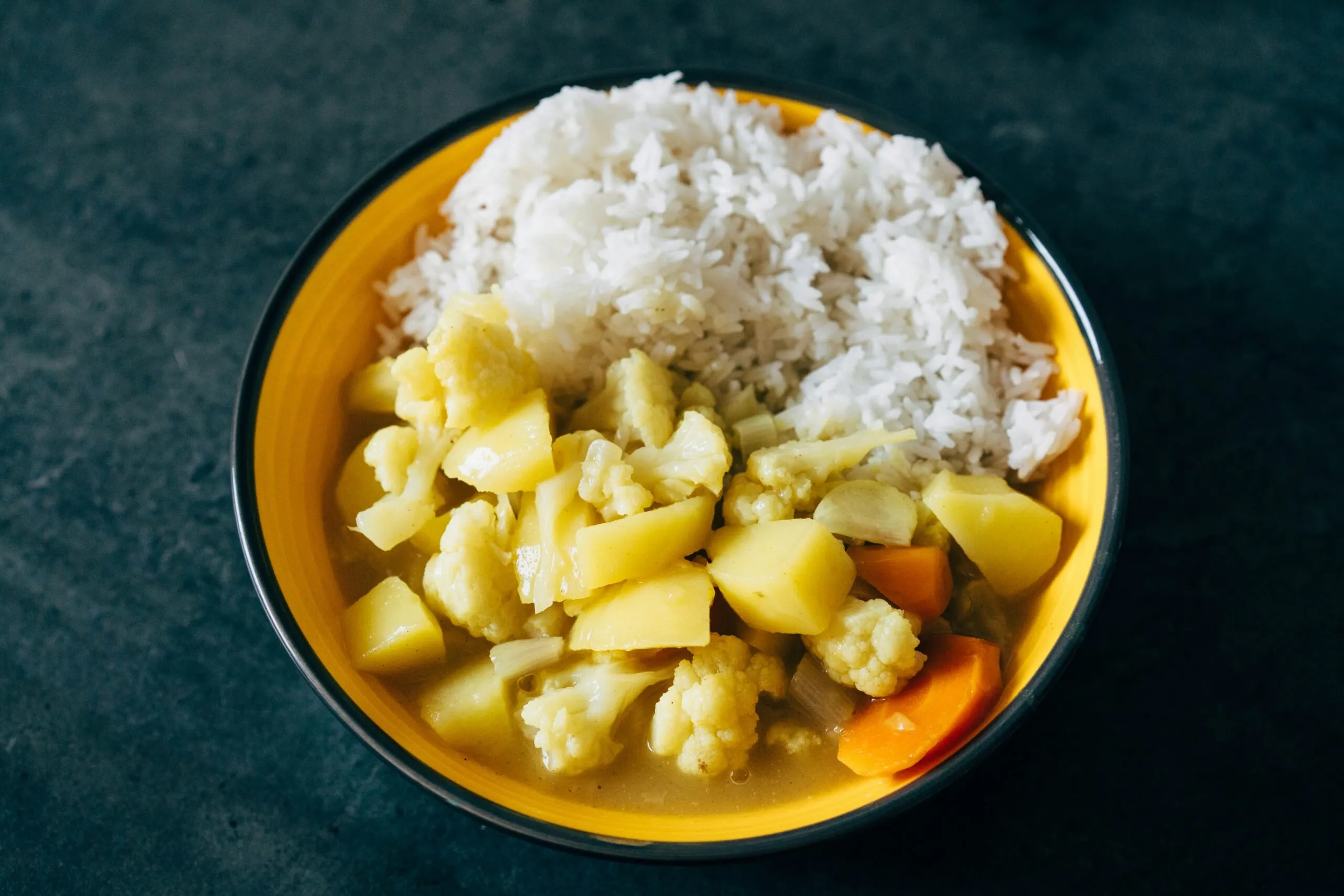 a yellow bowl filled with rice and vegetables