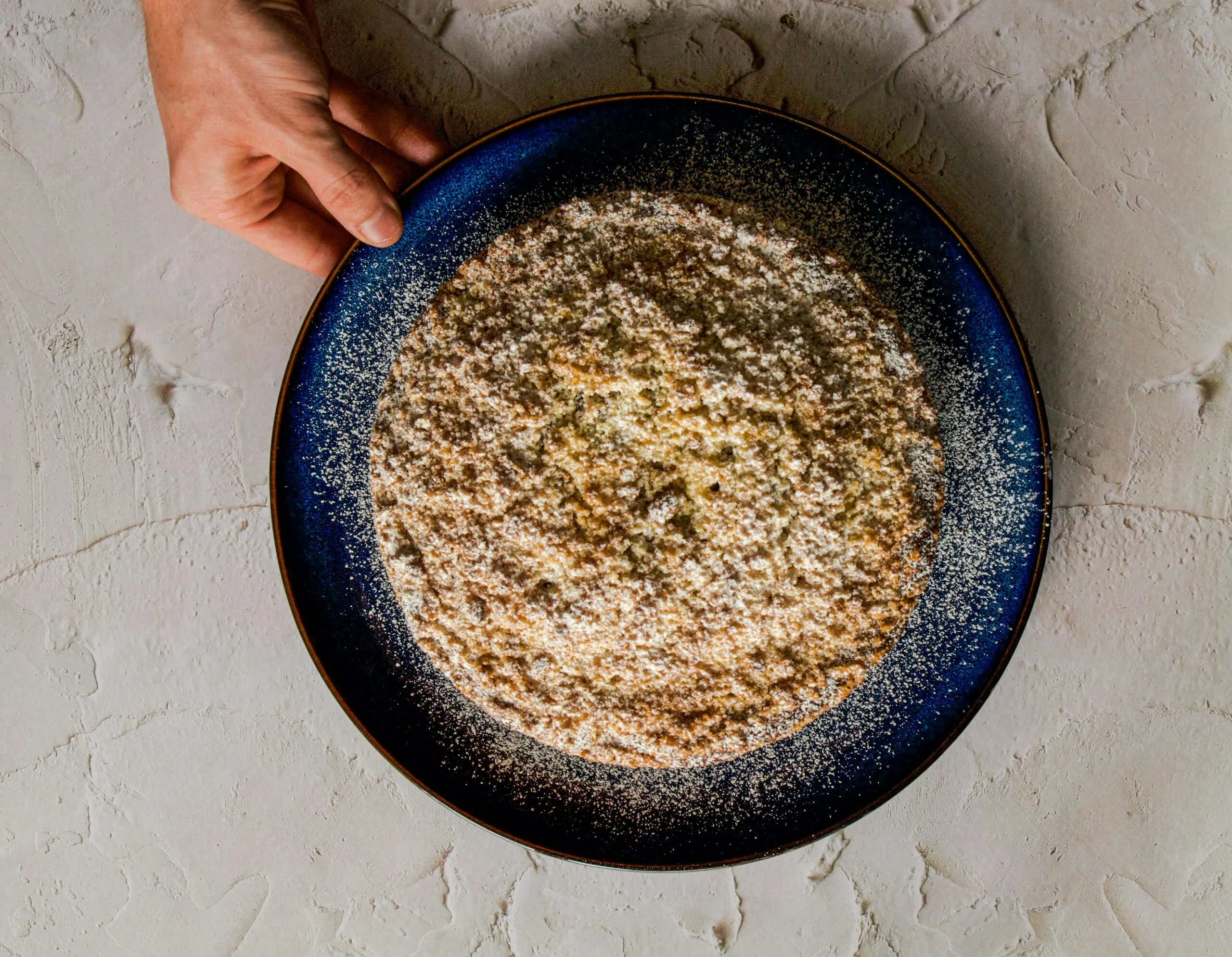 a person holding a plate of food on a table