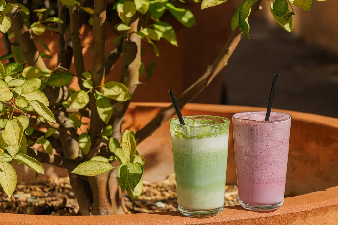 Two colorful smoothies in glasses with straws.