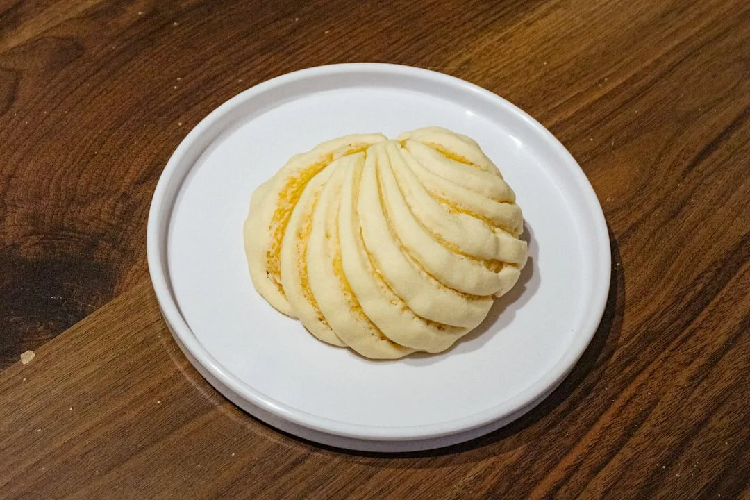 A white plate topped with sliced potatoes on top of a wooden table
