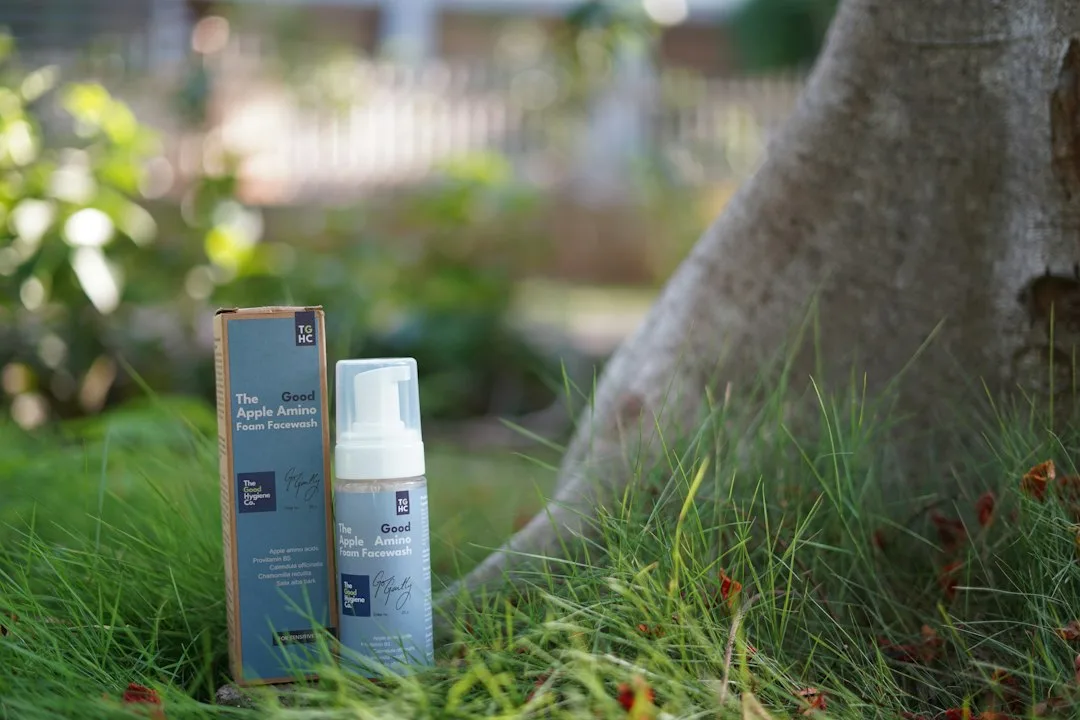 Foaming cleanser bottle and box near tree trunk