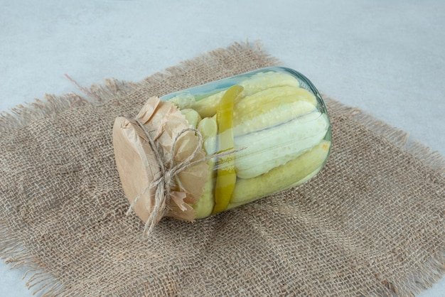 A jar of homemade pickled cucumbers on burlap.