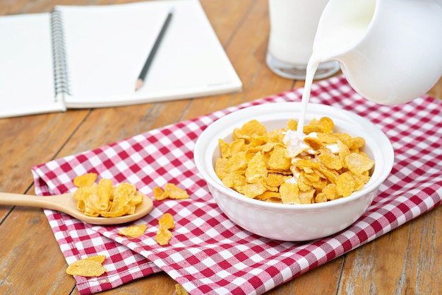 Milk pouring into a bowl of delicious corn flake cereals. 