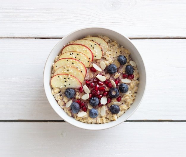 Oatmeal porridge with apple, pomegranate, blueberries and almonds. Healthy eating. Vegetarian food. Breakfast.