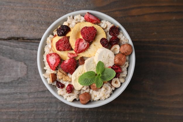 Oatmeal with freeze dried fruits nuts and mint on wooden table top view
