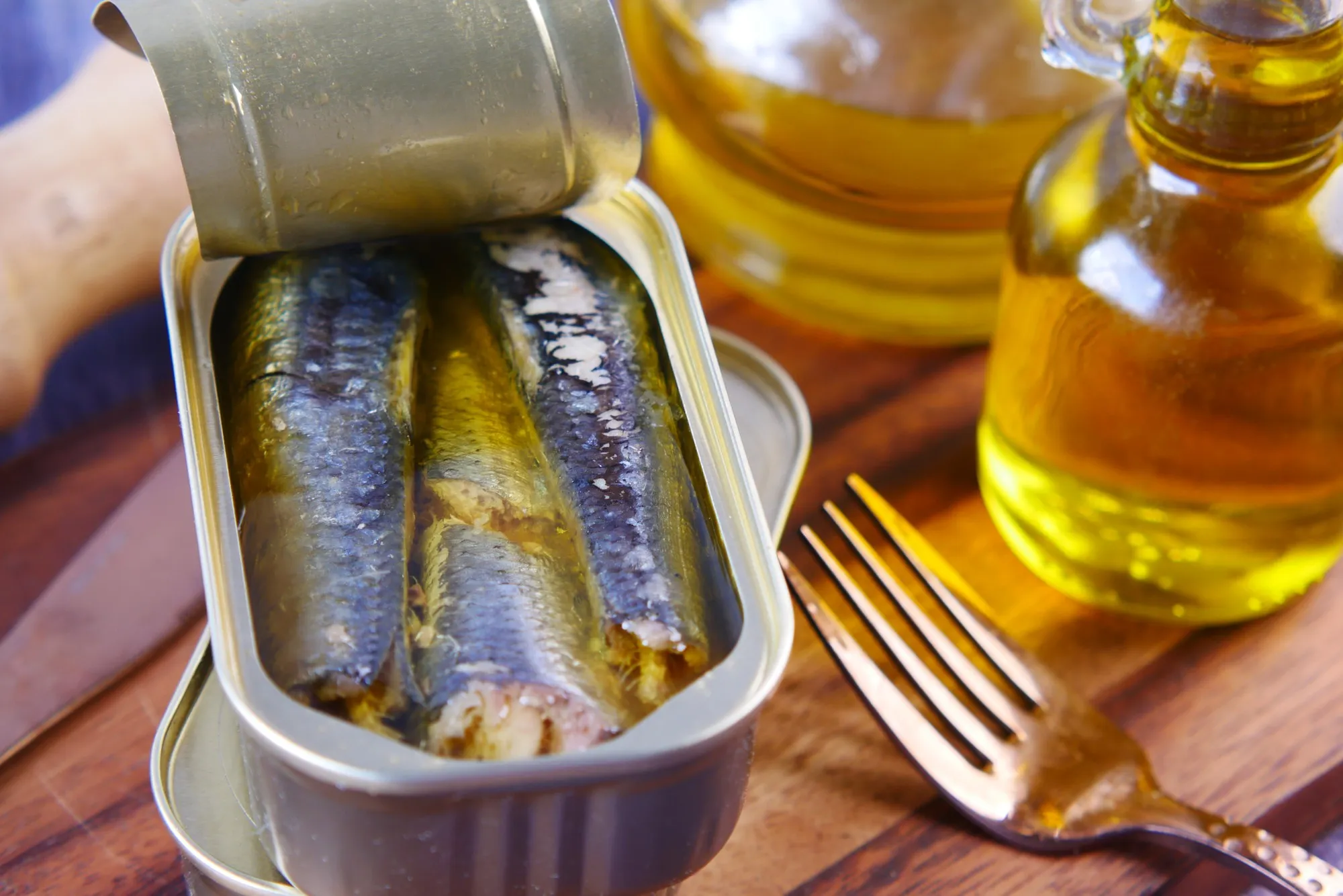 Open tin of sardines and olive oil on table