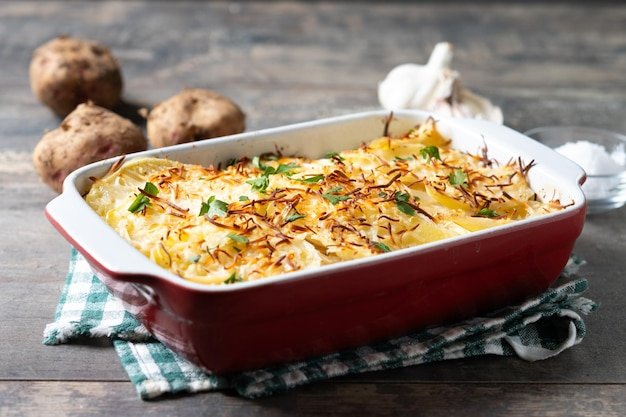 Potato gratin baked with cream and cheese on wooden table