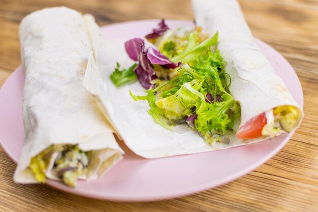 Preparation of a roll of pita bread and fresh vegetables on a wooden background The concept of healthy eating