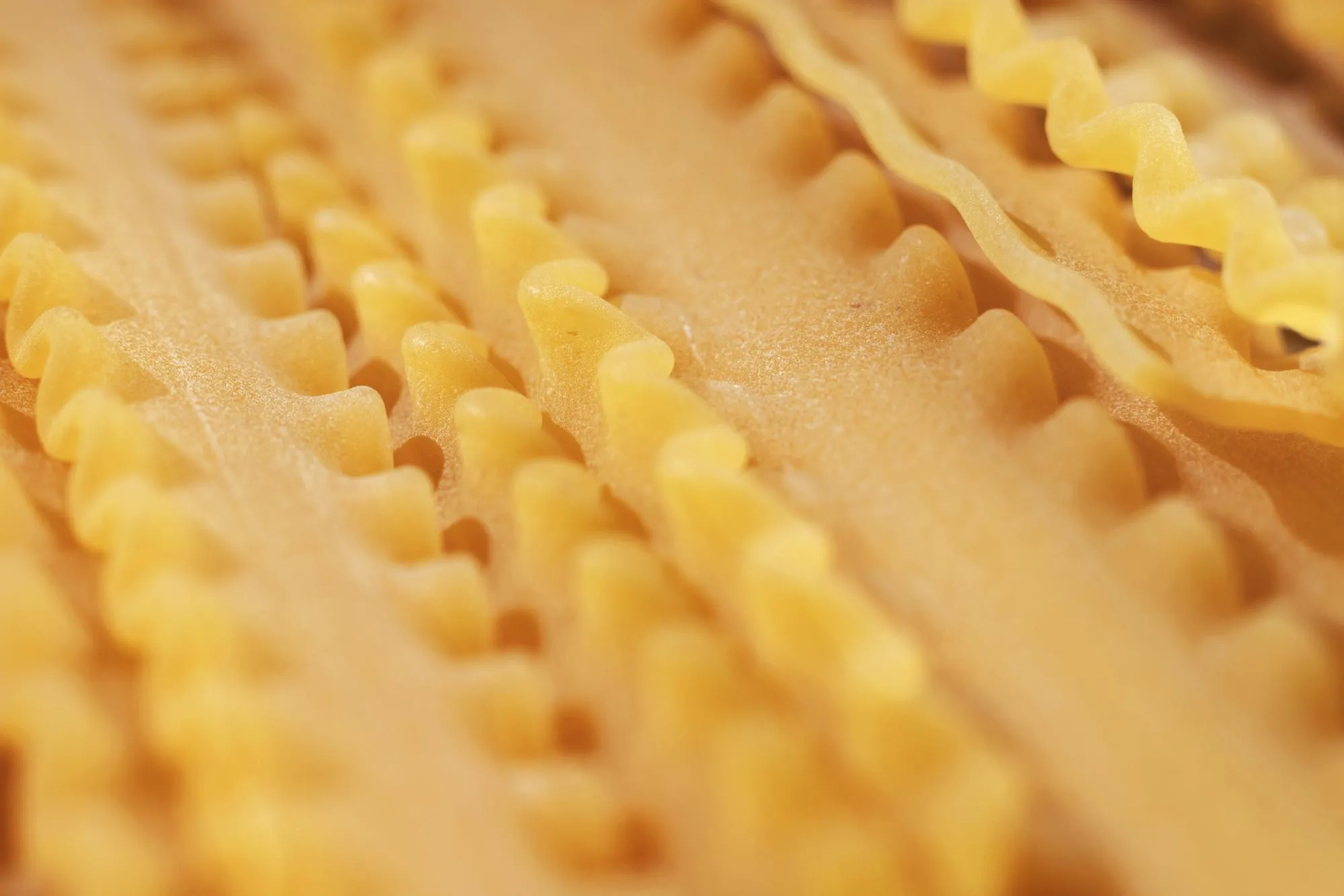 Raw italian pasta called mafaldine  flat and wide pasta with wavy edges   abstract effect