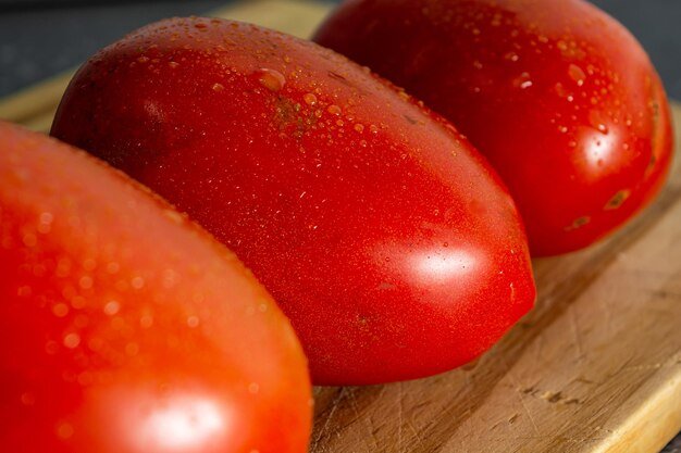 Red tomato with water drops on wooden cutting board