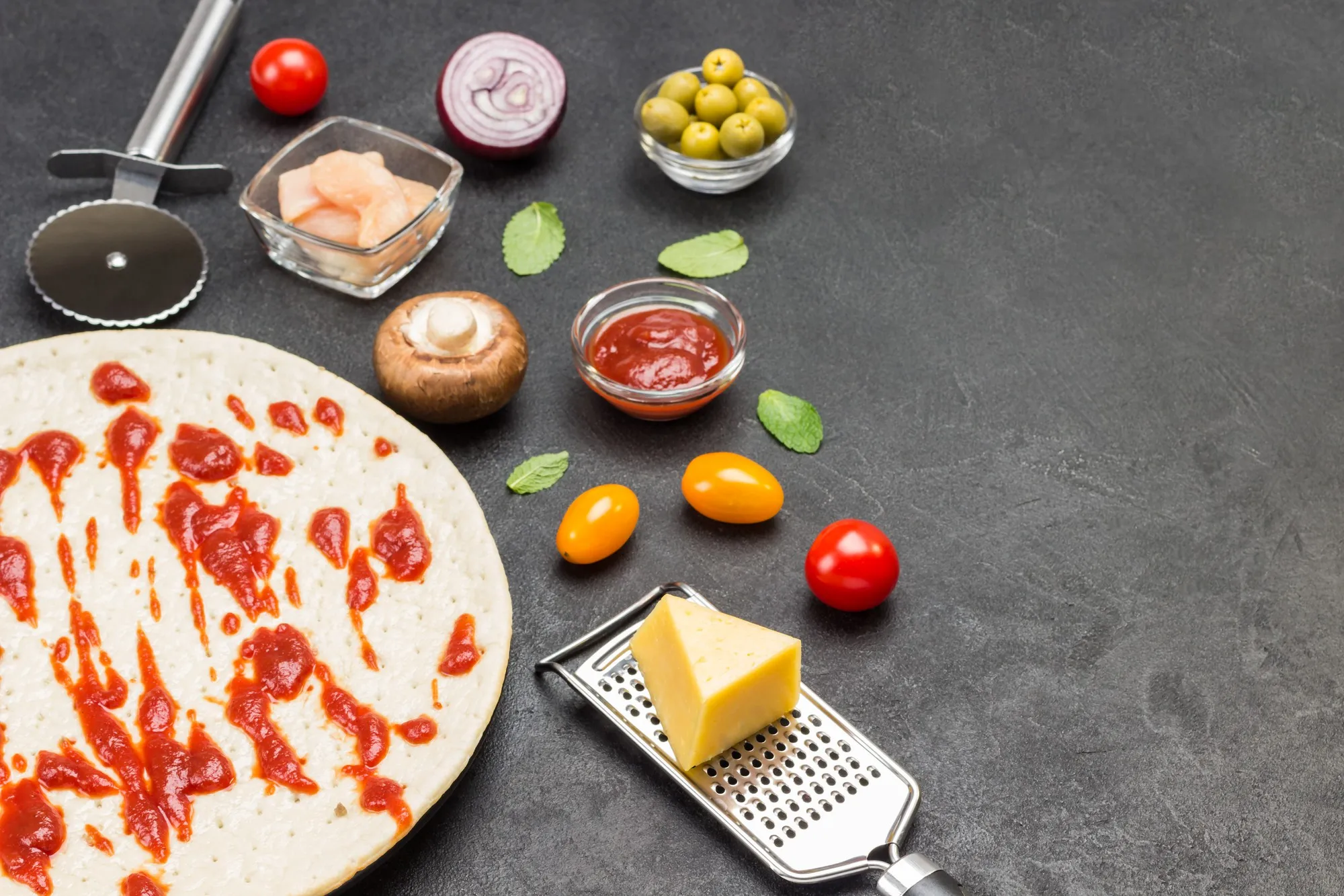 Round dough base for pizza and various ingredients