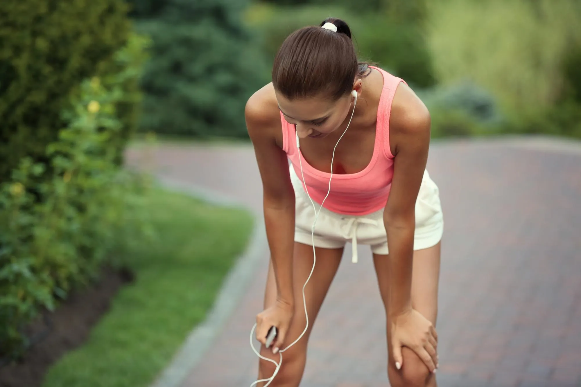 Sporty young woman resting after running in park