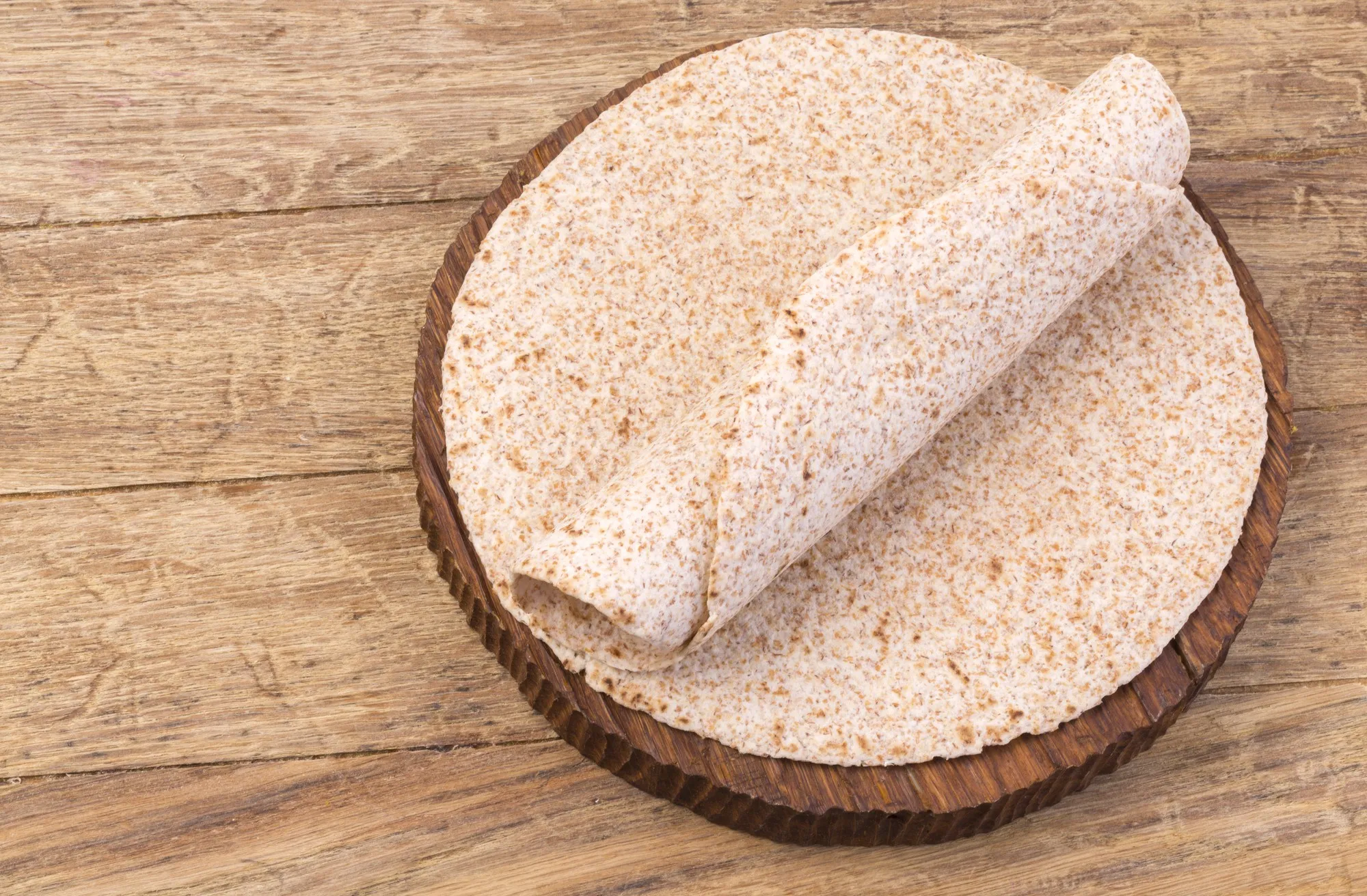 Stack of homemade whole wheat flour tortilla  on wooden table background