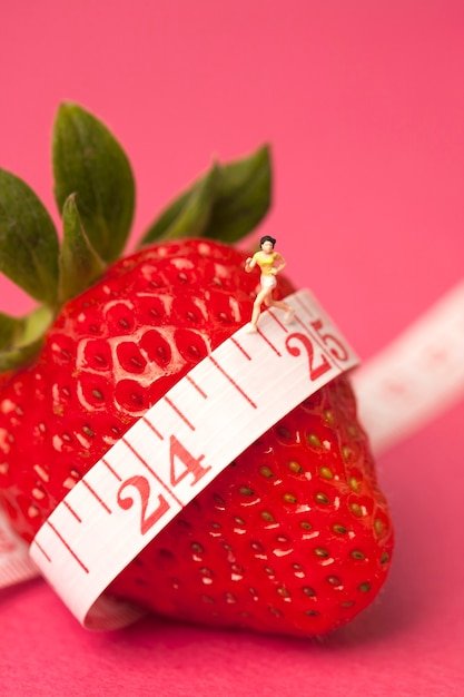Strawberry with measure tape on pink background