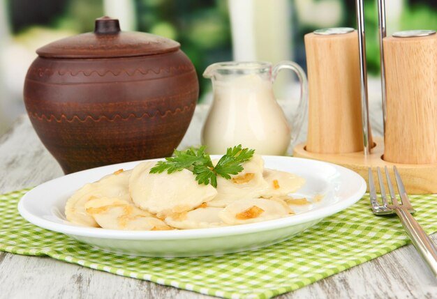 Tasty dumplings with fried onion on white plate on bright background