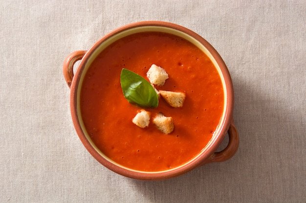 Tomato soup in brown bowl garnished with croutons top view