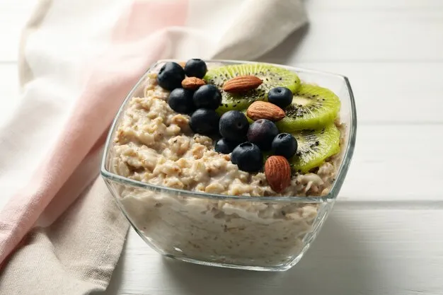 Towel and bowl with oatmeal porridge and fruits on wooden