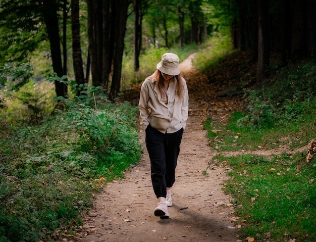 Woman in beige hat tilted her head and laughs while walking in the park