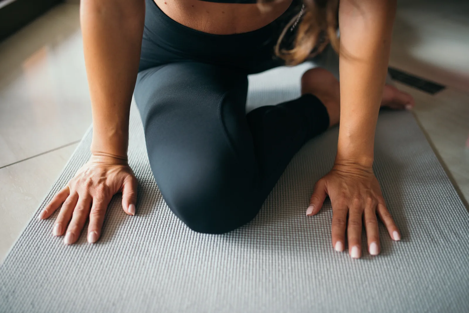 Closeup of the woman on a yoga mat stretching her hips.