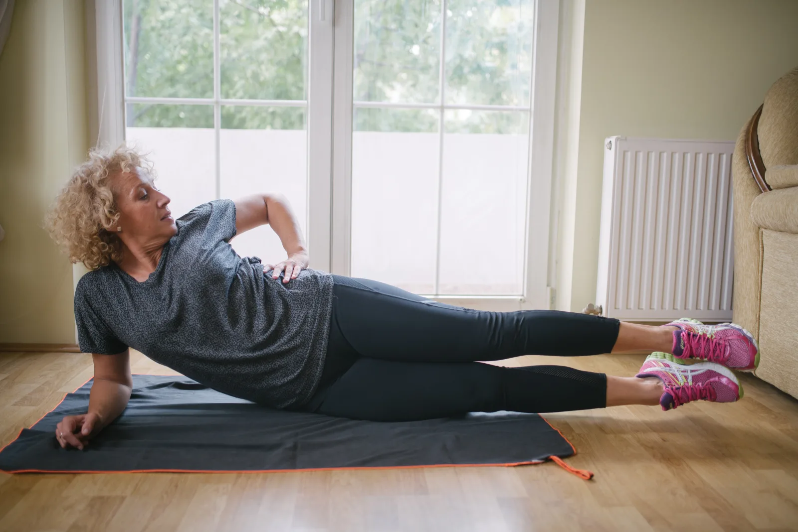 Woman doing hip exercises on a yoga mat on the floor
