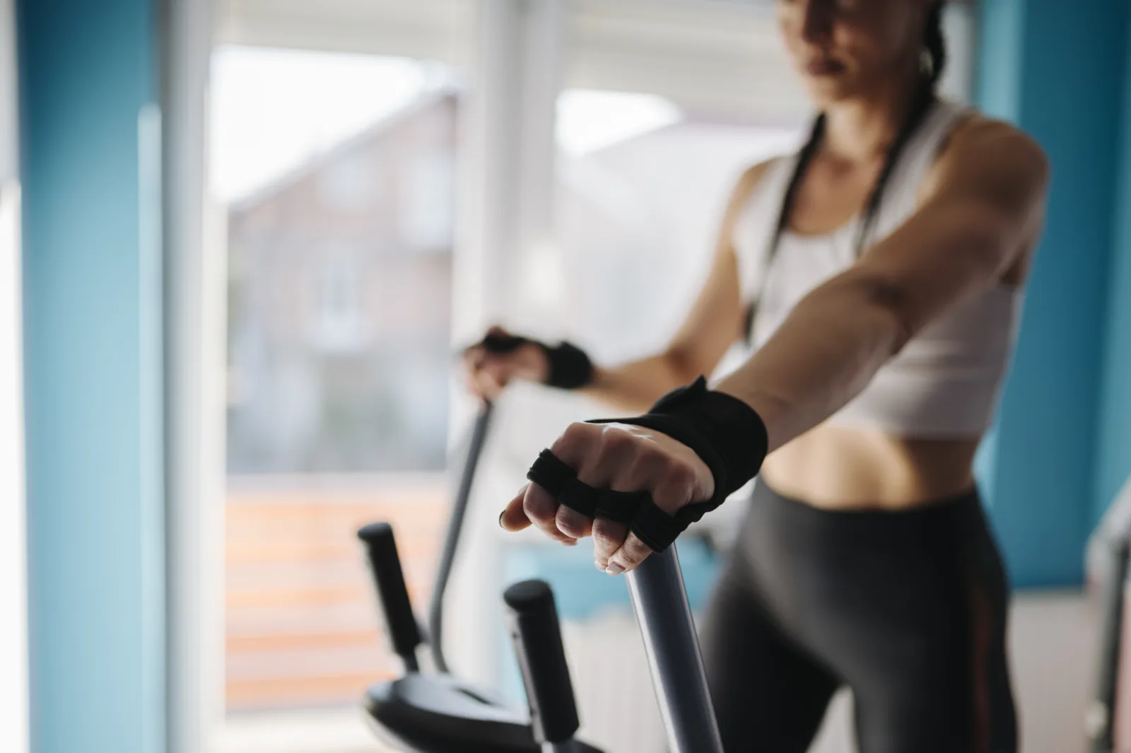 Woman exercising on an elliptical machine in a bright indoor gym closeup