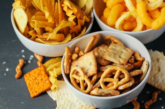 Beer snacks on stone table. Various crackers, potato chips. Top view 