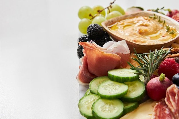 Cheese board with hummus fruit and vegetables on a white background