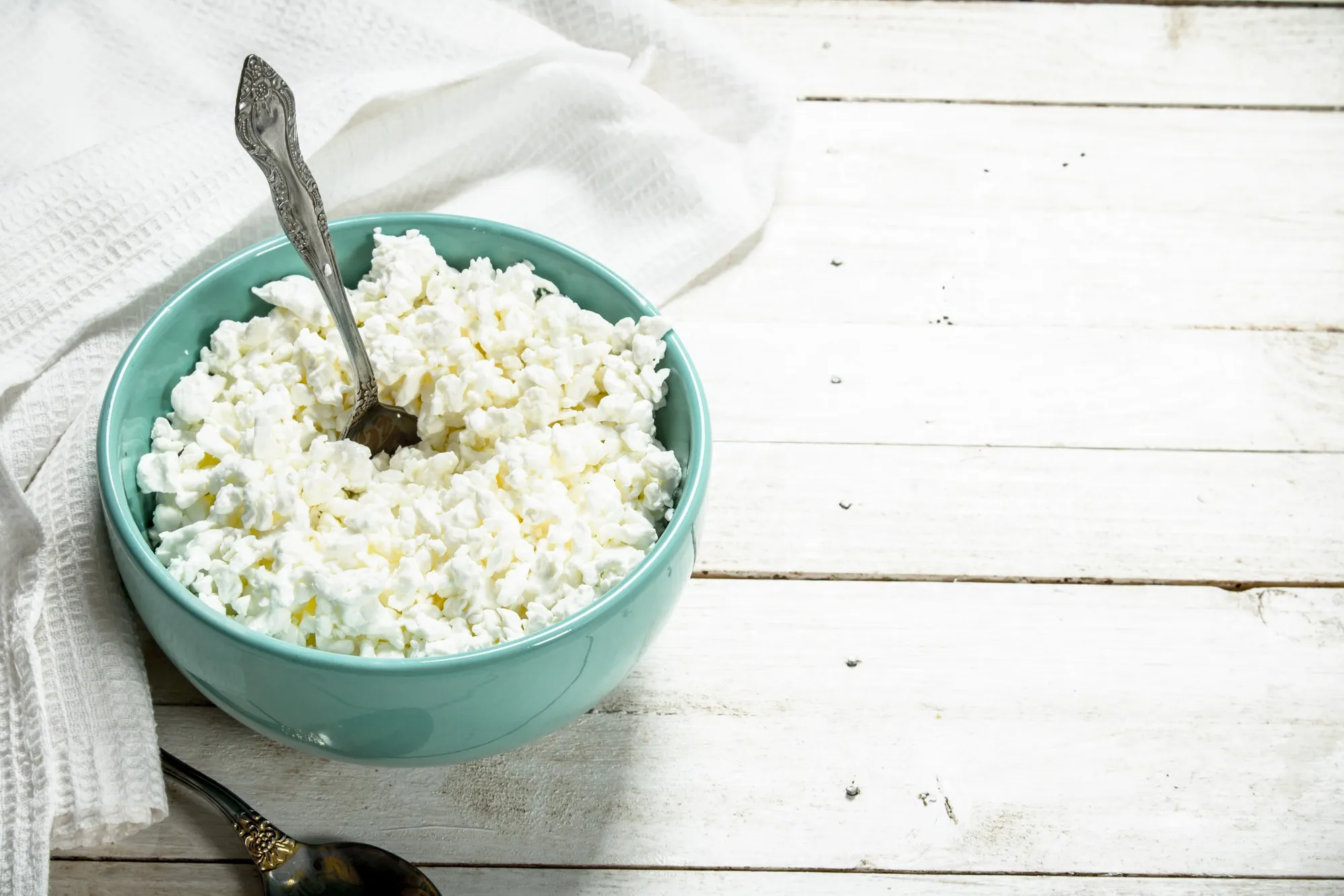 Cottage cheese from fresh milk in a bowl. On a white wooden table.