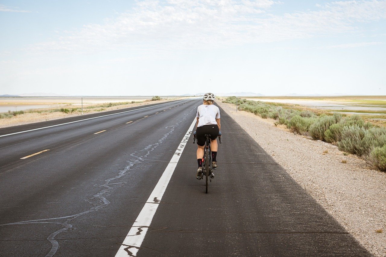 cyclist, cycling, biking, bike riding, road, pavement, highway, asphalt road, desert, bike, bicycle, exercise, leisure, fitness, nature, activity, sport, outdoors, woman