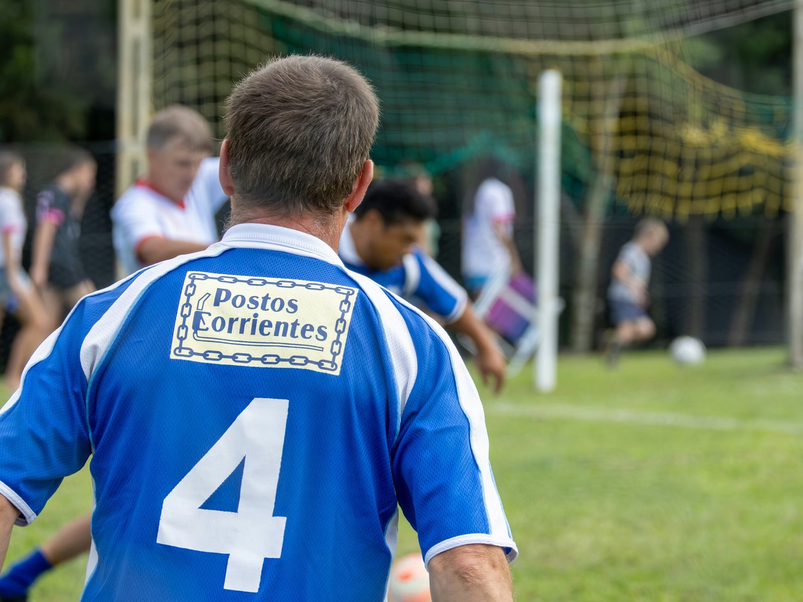 Soccer players on a grassy field near a goal.