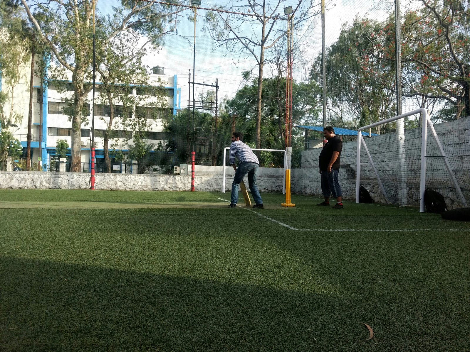 Two men playing cricket on a turf field.
