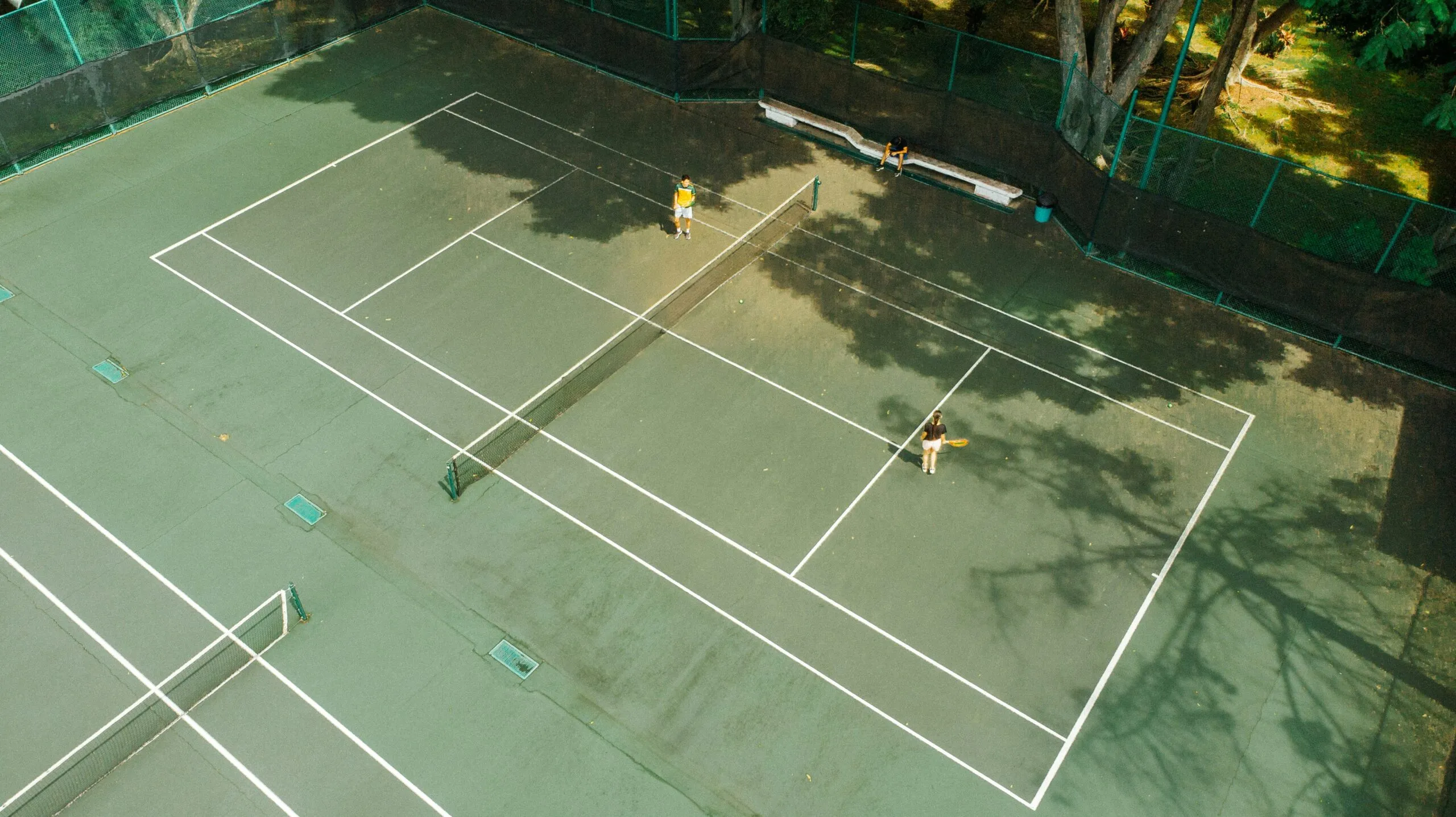 Two people playing tennis on an outdoor court.