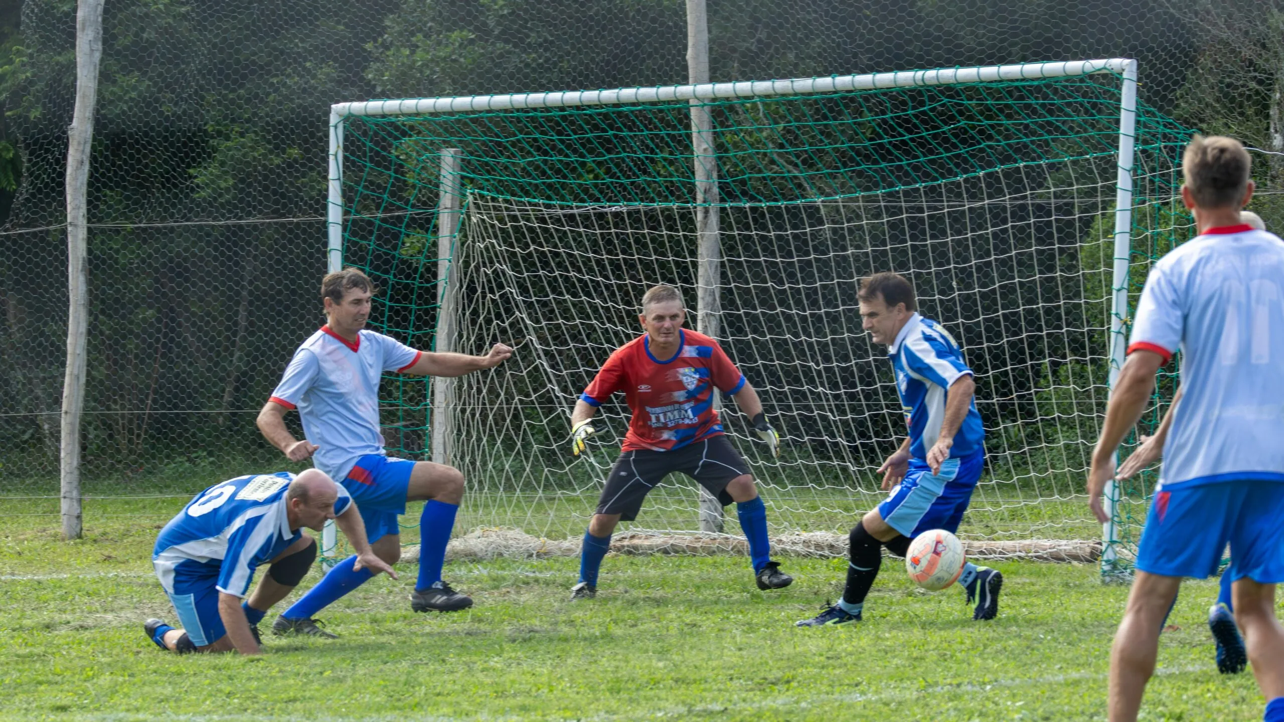 Soccer players compete for the ball near the goal.
