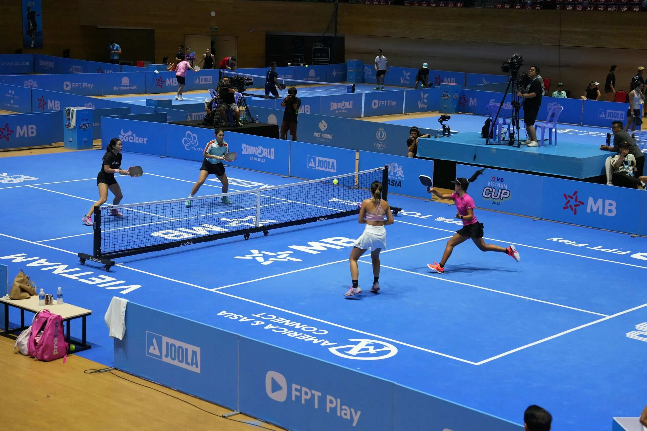 Players compete in a pickleball match on a blue court.