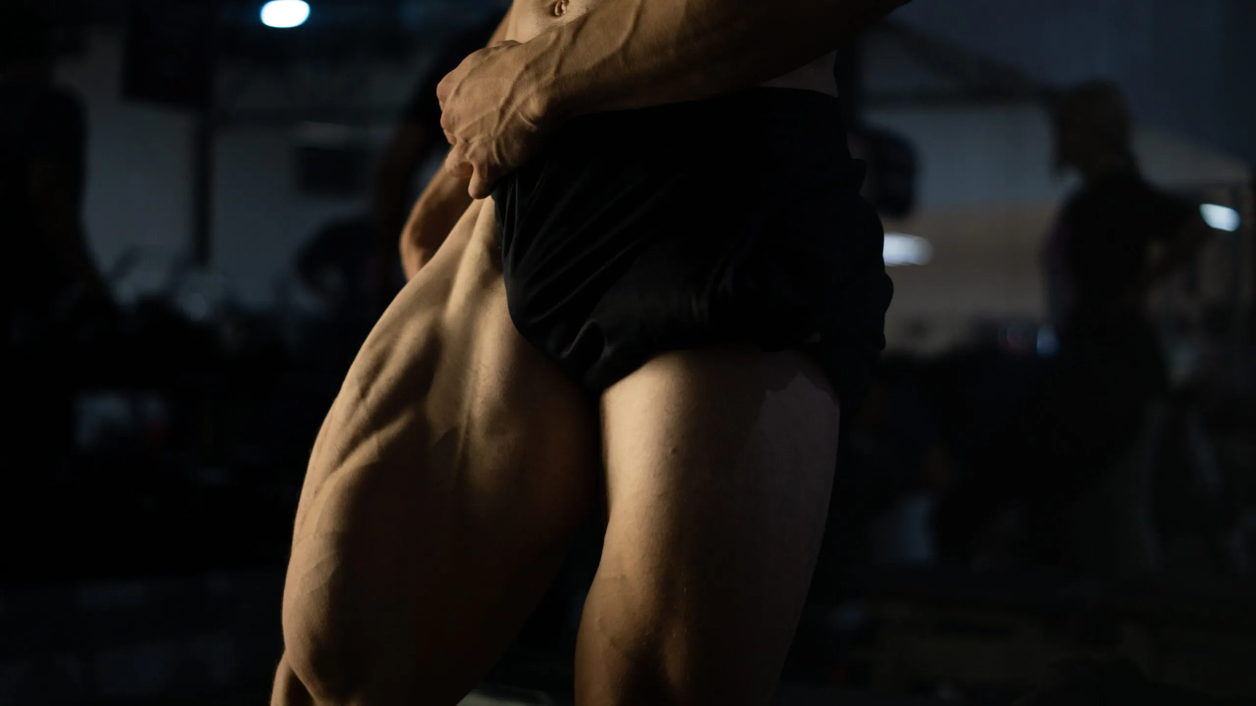 Dynamic close-up of a man's muscular thighs in a gym environment, highlighting strength.