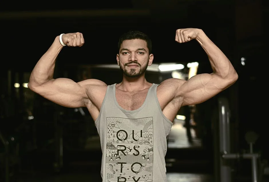 A fit man flexing his biceps in a gym environment, showcasing strength and fitness.