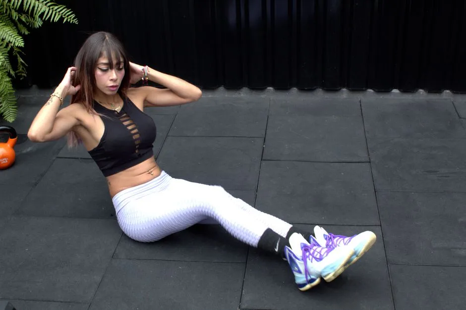 Adult woman performing exercises in gym with kettlebell in sportswear. Fitness and health concept.