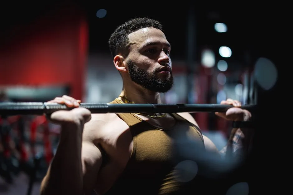 Muscular man in a gym focused on lifting a barbell, highlighting strength and fitness.