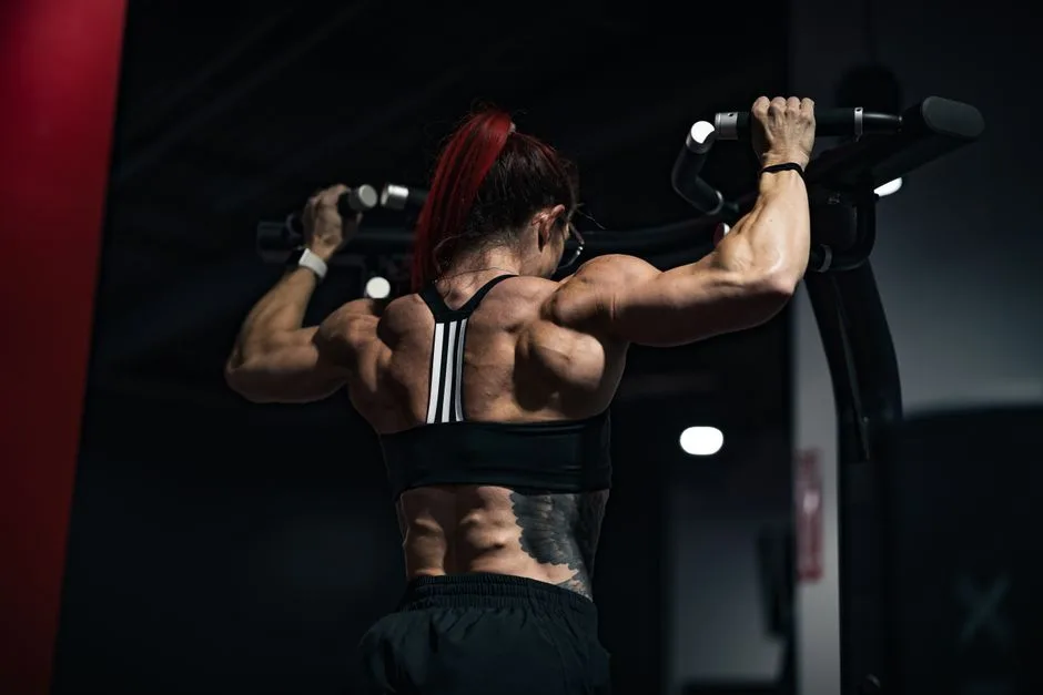 Back view of a muscular woman lifting weights in a gym, showcasing strength and determination.