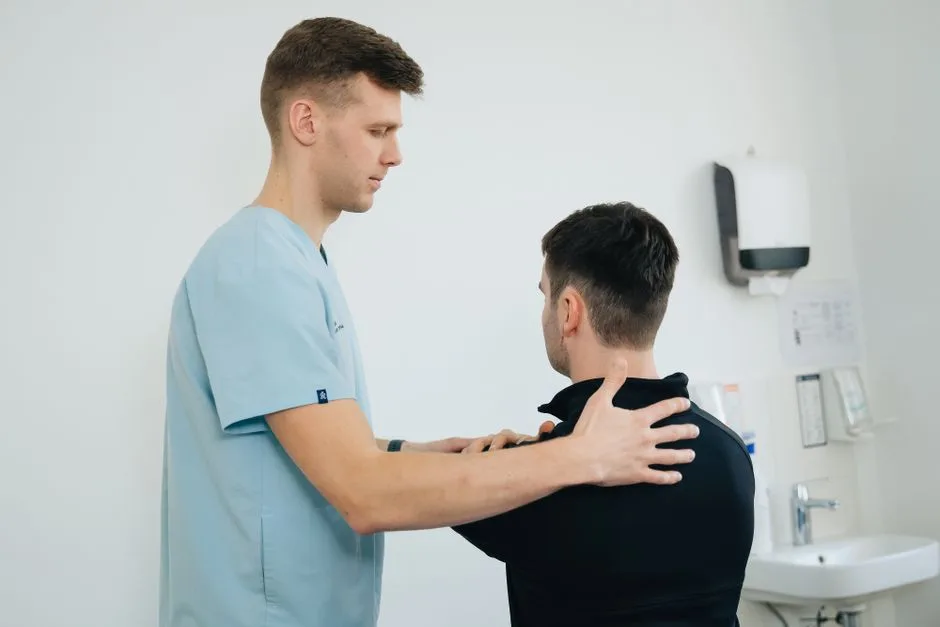 Physiotherapist working with a patient in a clinical setting, focusing on shoulder therapy.
