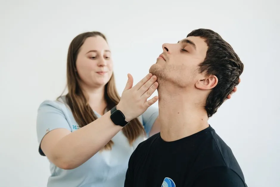 A physiotherapist performs therapy on a male patient's neck in Vilnius clinic.