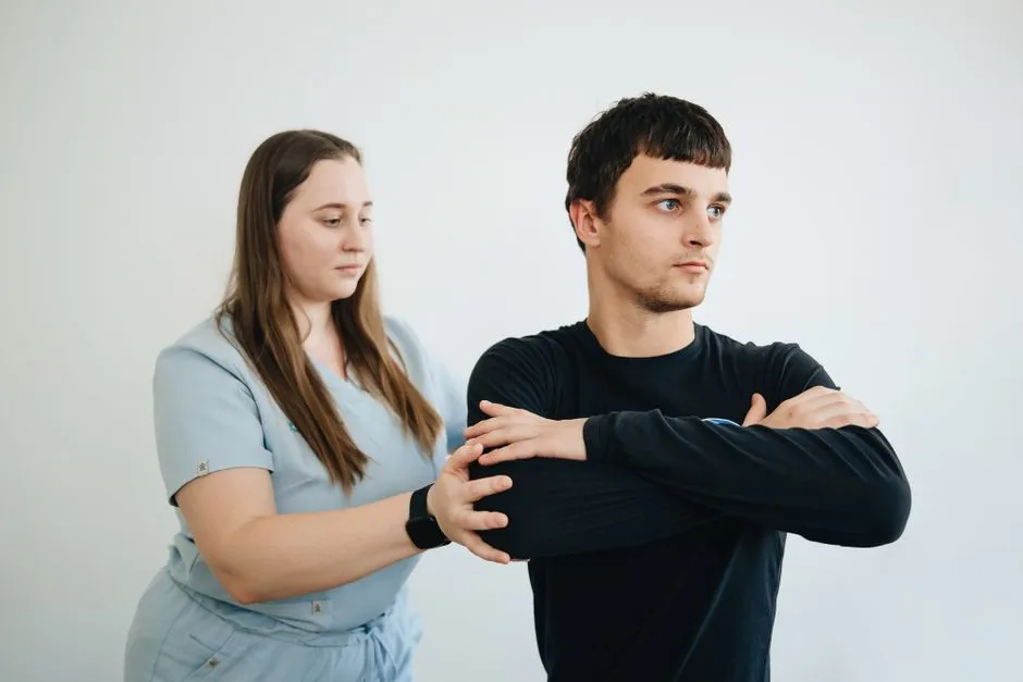 A physiotherapist assists a patient with arm exercises in a clinical setting.