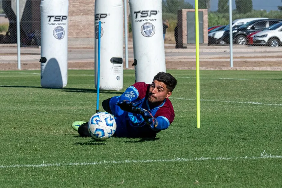 Goalkeeper in action diving to save a soccer ball during practice on a sunny day.
