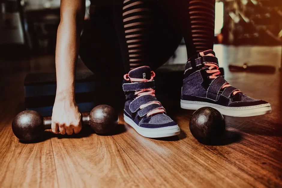 A person in striped leggings prepares for a workout with dumbbells indoors.
