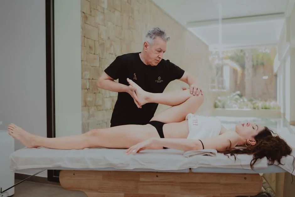 A therapist assists a patient during a rehabilitation session indoors, promoting mobility and flexibility.