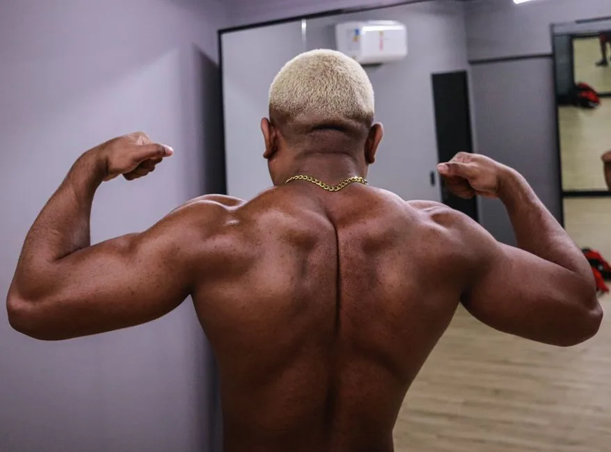 A fit man showcasing his muscular back in a gym environment, emphasizing strength.