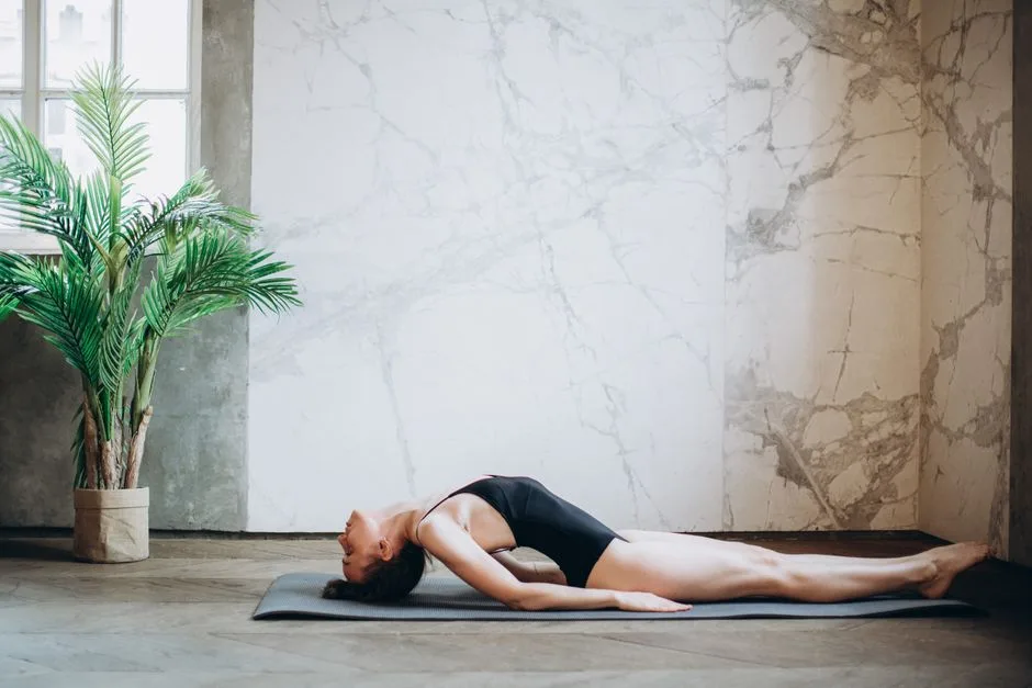 Woman performing yoga backbend exercise inside a stylish modern room.