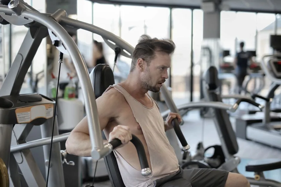 Side view of determined athletic male in sportswear pumping muscles during workout in fitness center and using shoulder press machine