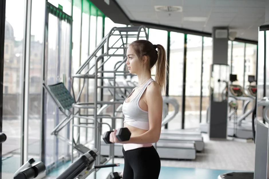 Fit young woman working out with dumbbells in a well-equipped modern gym.